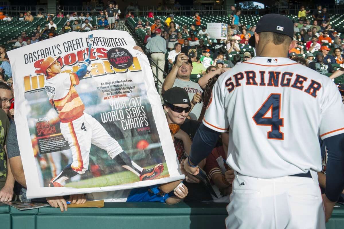 PHOTOS: Houston teams featured on the cover of Sports Illustrated A Houston Astros fan holds up a large print of the Sports Illustrated cover featuring right fielder George Springer as he signs autographs before a game against the Seattle Mariners.