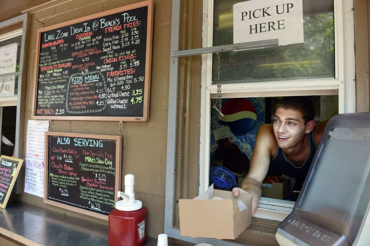 Jared Epstein, of Trumbull, serves up an order of fries Tuesday, July 1, 2014, at the concession stand at Robert G. Beach Memorial Park in Trumbull, Conn. Mike Basso, owner of Lake Zoar Drive-In in Monroe, has taken over the food stands at both outdoor Trumbull pools.