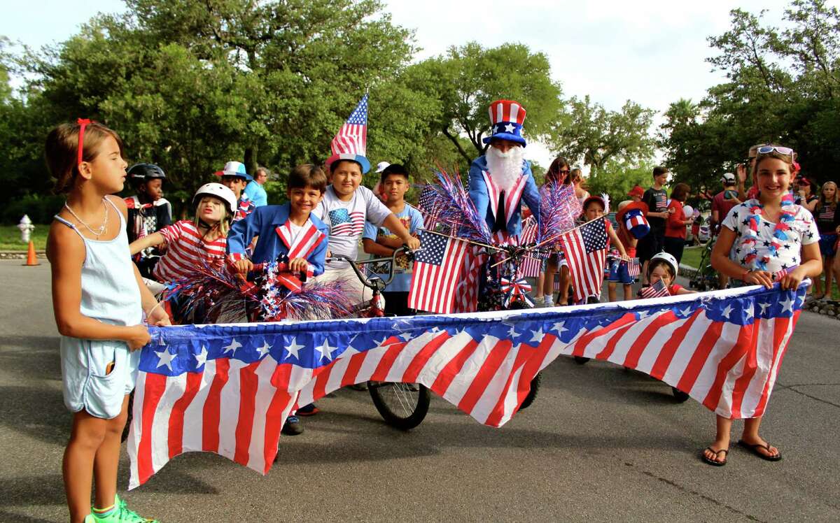 Locals hit Olmos Park to brandish banners, wear funny hats, wave flags, wish America a happy birthday and celebrate freedom from the British.