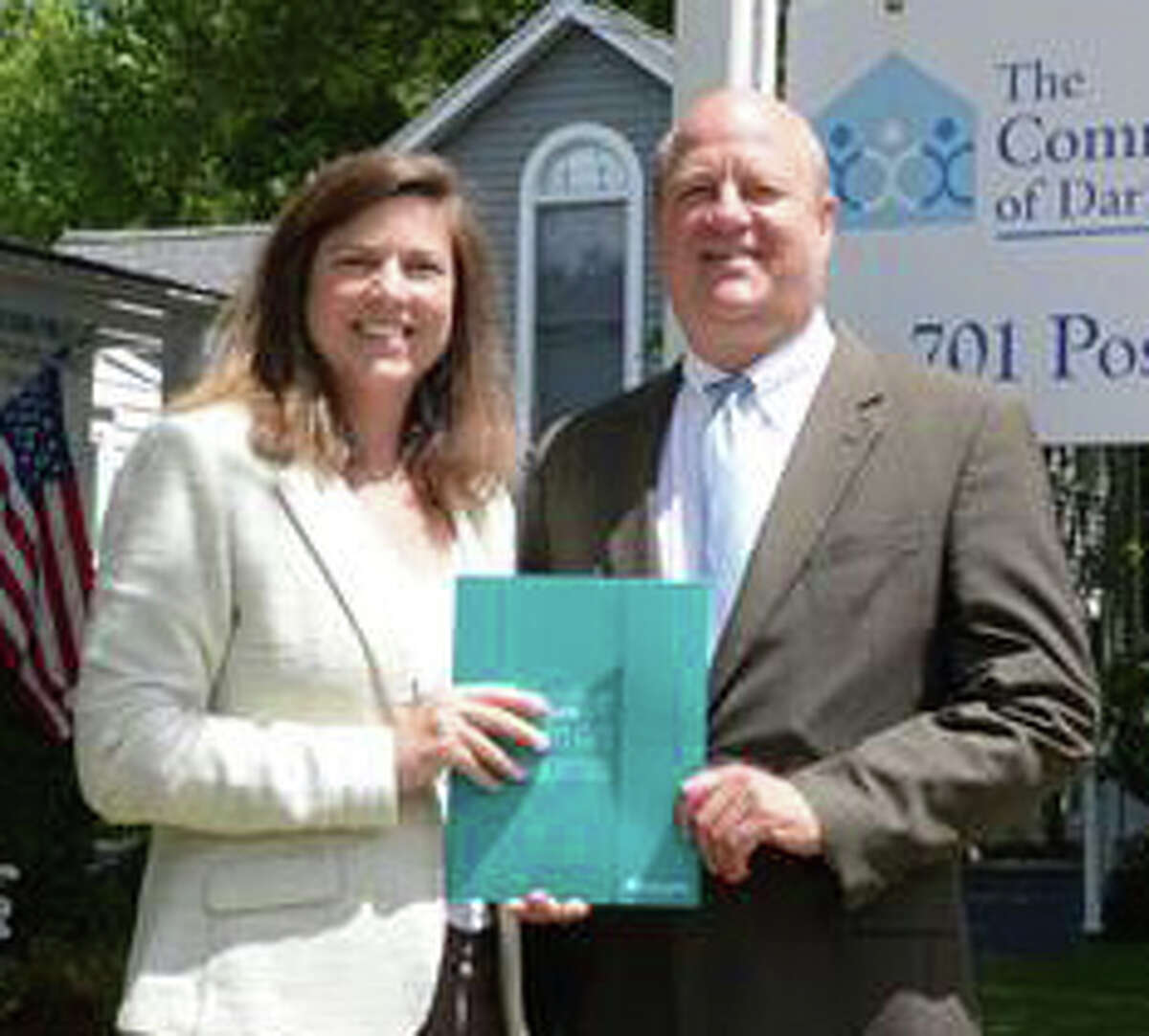 Carrie Bernier, executive director of The Community Fund of Darien, accepts a donation from Mark Rosenbloom, of First County Bank