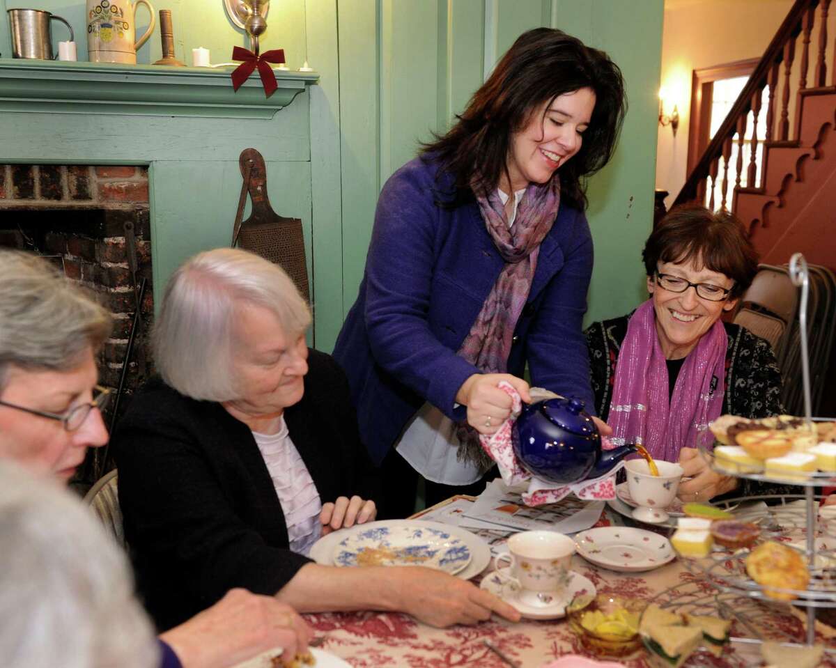 Brigid Guertin, standing, executive director of the Danbury Museum and Historical Society, on Main Street in Danbury, Conn., serves tea at the museum's annual fundraiser, "Holiday Tea in the Rider House." From left are Barbara Lynch, Kathy Jacocks and Mary Tomaino, all of Danbury.
