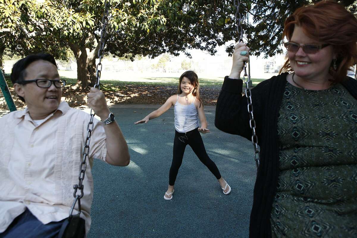 Chino Scott-Chung, left, and Maya Scott-Chung play on the swings San Antonio Park with their daughter Luna(9) in Oakland, CA, Thursday, July 3, 2014.