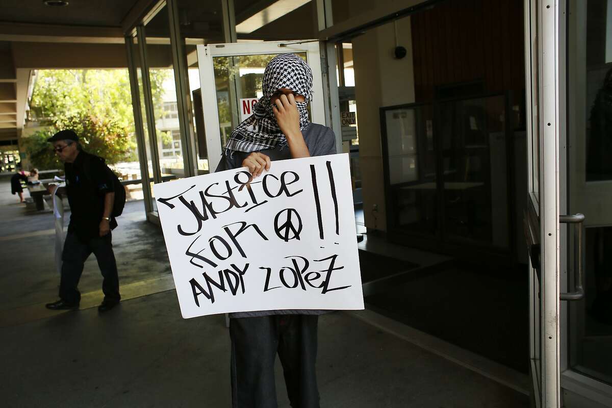 A protester covers his face as he holds a sign outside the courtrooms 1-13 and district attorney entrance July 8, 2014 outside of the Sonoma County Hall of Justice in Santa Rosa, Calif. People gathered to protest D.A. Jill Ravitch to let her know that they are unhappy with the lack of charges in the case involving the death of Andy Lopez last year.