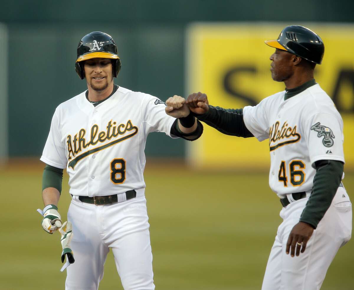 Jed Lowrie (8) gets a high five from first base coach Ty Waller after he got a hit in the third inning as the Oakland Athletics played the San Francisco Giants on Tuesday, July 8, 2014, at O.co Coliseum in Oakland, Calif.