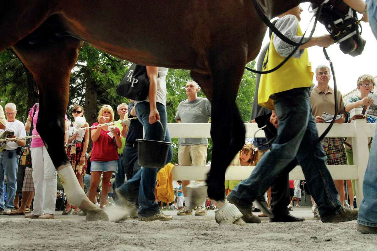 A crowd gathers to watch horses on their walk to the paddock before the 5th race at Saratoga Race Course on opening day in Saratoga Springs, New York (Michael P. Farrell / Times Union ) published 7/30/2009