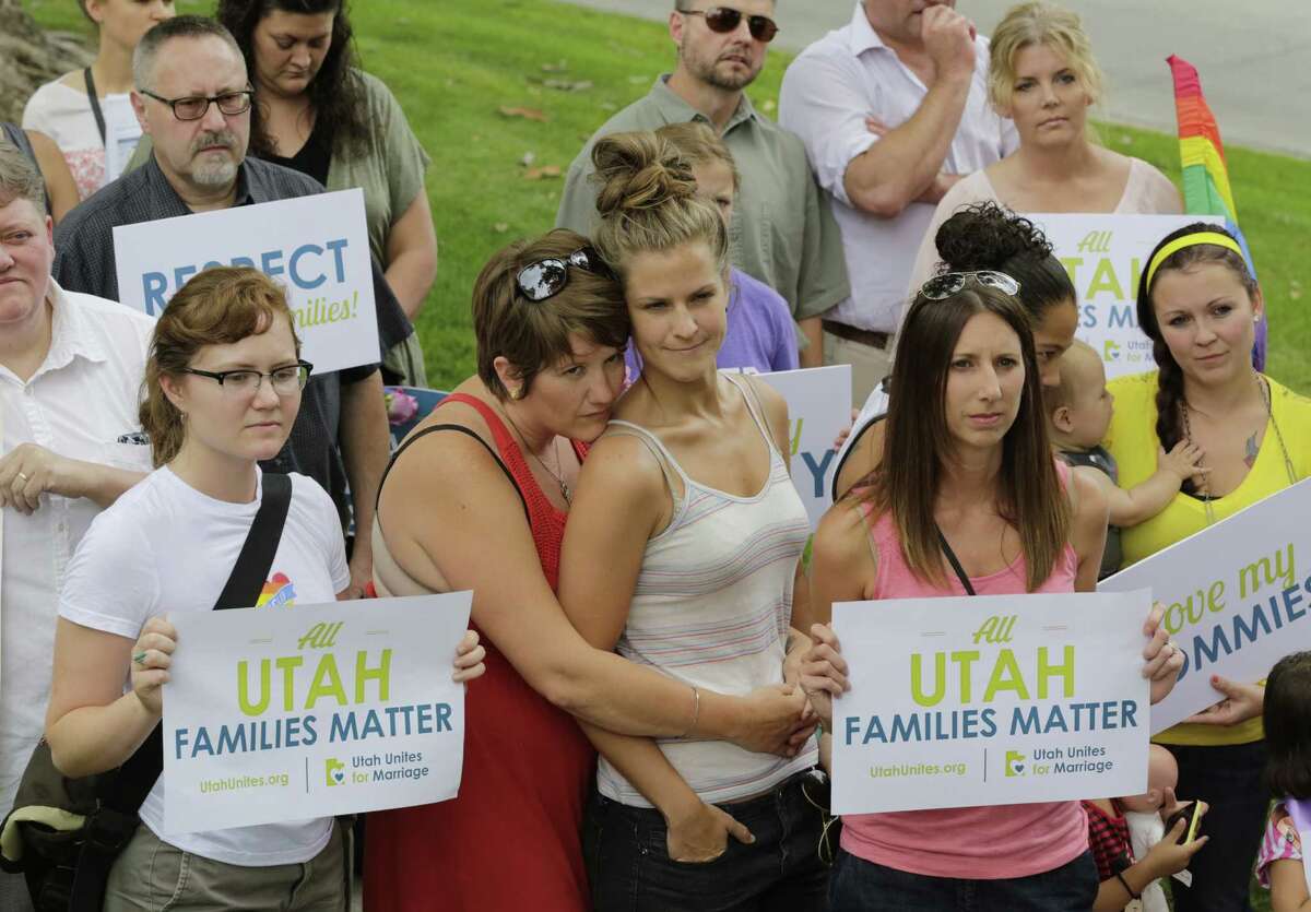 People look on as they gather with about 50 same-sex marriage advocates while delivering a petition with thousands signatures to the governorâs mansion pushing for recognition of gay married couples Wednesday, July 9, 2014, in Salt Lake City. Outside the mansion, gay couples said they should receive the same benefits as others in Utah. The group included a handful of families whose children helped to dump the letters into a cardboard box received by state aides. (AP Photo/Rick Bowmer)
