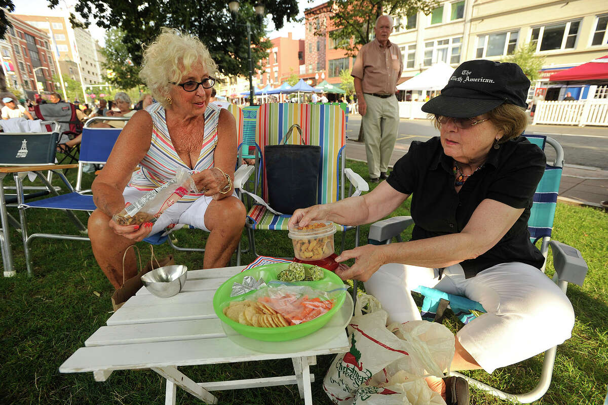 Carole Nichols, left, and Linda Kennedy set out picnic food as Carole's husband, Bob located in the background, returns to his seat during Jazz Up July at Columbus Park in Stamford, Conn., on Wednesday, July 9, 2014. Hearst Connecticut Media Group is a sponsor of the event.