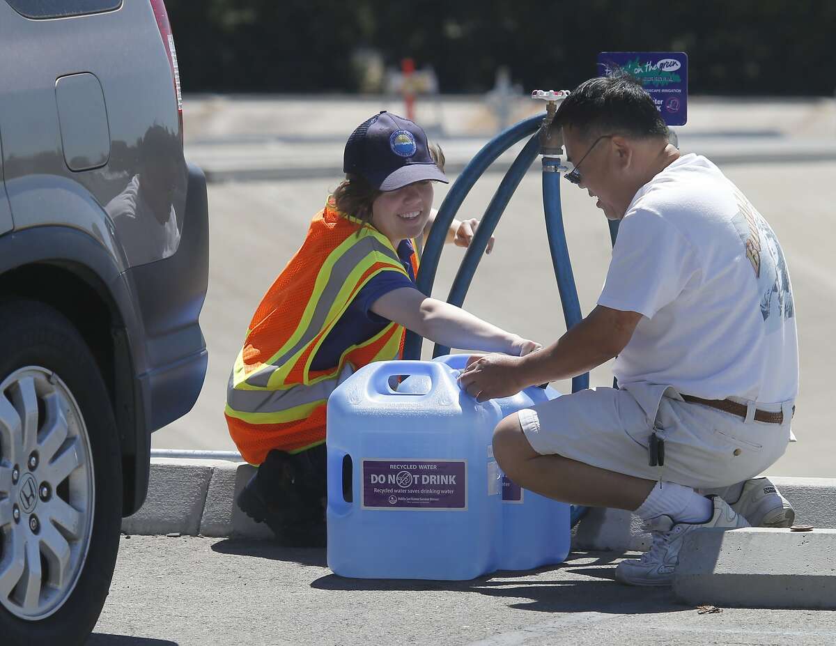 Water attendant Krtisti Kolodzie at the Dublin San Ramon Services District (left) helped resident Terry Chi with recycled water for his garden Wednesday July 9, 2014. State officials are stepping up their push for water conservation with plans to levy fines of as much as $500 a day against people who waste water outdoors.