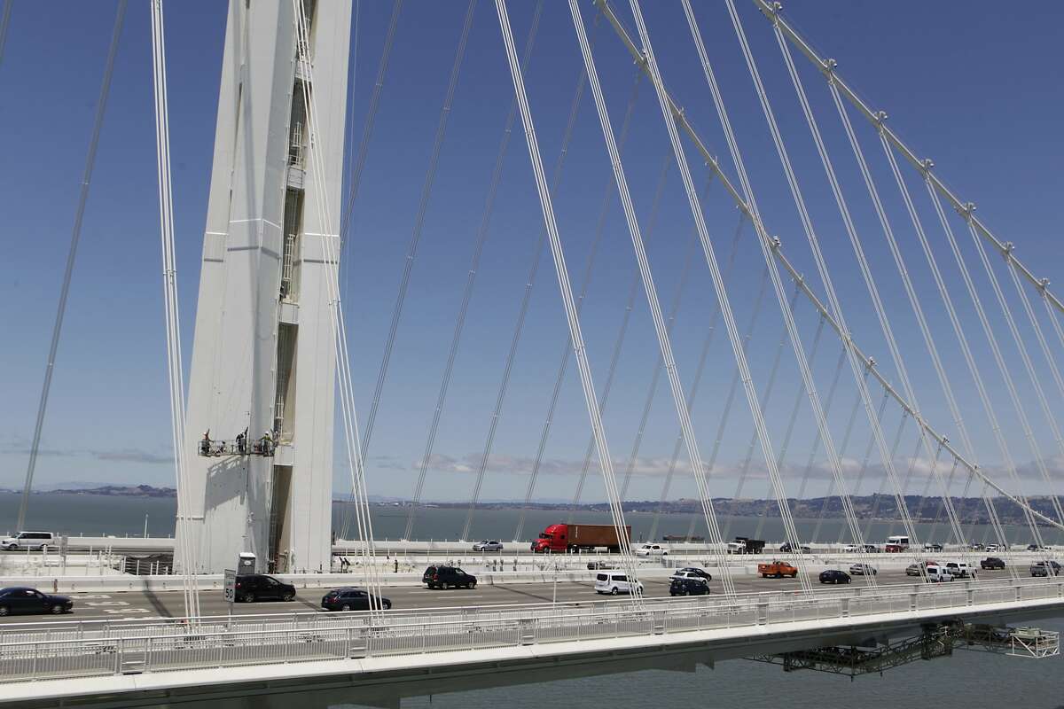 Eastbound commuters drive past bridge crews repainting the SAS tower of the new eastern Bay Bridge span in San Francisco, Calif. on Thursday, July 10, 2014.