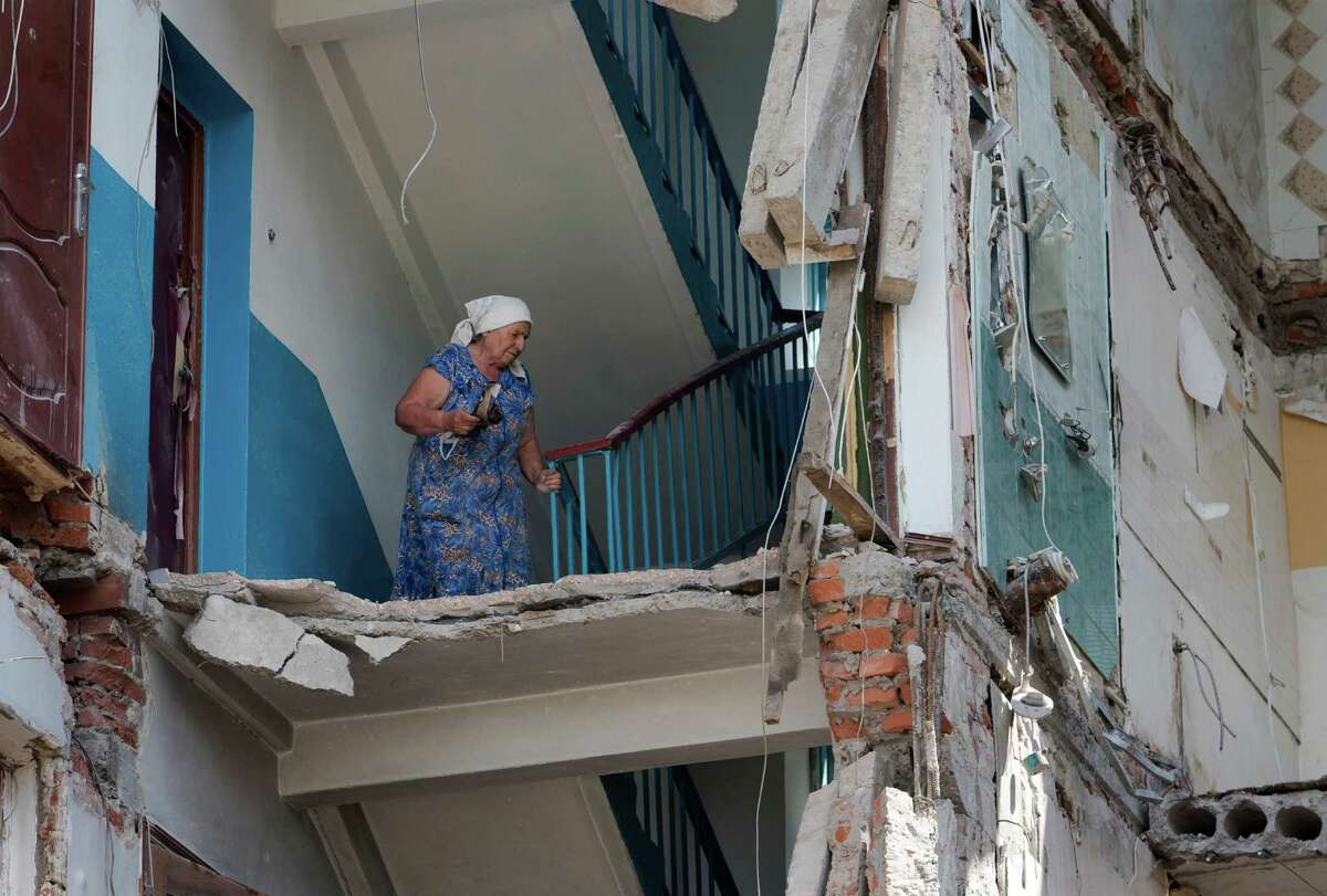 An elderly woman comes back to her flat in a building damaged by shelling in Mikolaivka village, near the city of Slovyansk, Donetsk Region, eastern Ukraine Thursday, July 10, 2014. In the past two weeks, Ukrainian government troops have halved the amount of territory held by the rebels. Now they are vowing a blockade of Donetsk. In another sign of deteriorating morale among rebels, several dozen militia fighters in Donetsk abandoned their weapons and fatigues Thursday, telling their superiors they were returning home.(AP Photo/Dmitry Lovetsky)
