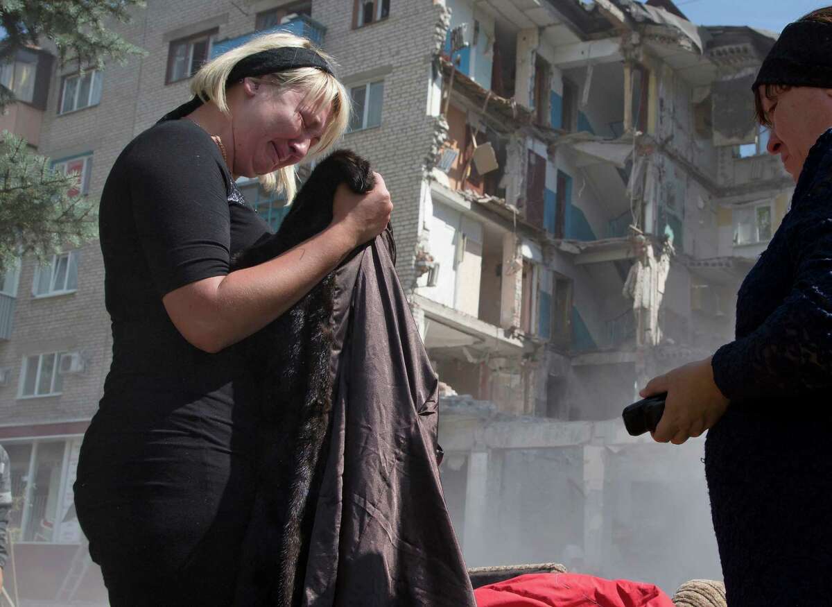 Eugenia Gubareva, left, cries after finding clothes belonging to her parents, who were killed in a building destroyed by shelling in Mikolaivka village, near the city of Slovyansk, Donetsk Region, eastern Ukraine Thursday, July 10, 2014. In the past two weeks, Ukrainian government troops have halved the amount of territory held by the rebels. Now they are vowing a blockade of Donetsk. In another sign of deteriorating morale among rebels, several dozen militia fighters in Donetsk abandoned their weapons and fatigues Thursday, telling their superiors they were returning home.(AP Photo/Dmitry Lovetsky)