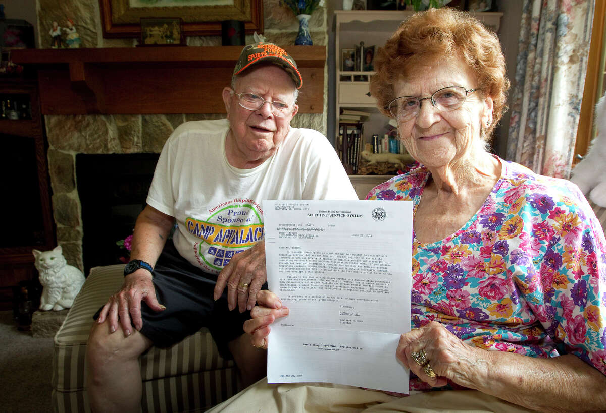 In this photo taken on Tuesday, July 8, 2014, Harold Weaver sits behind his wife, Martha, in their Nickleville, Pa, home. Martha holds a letter from the Selective Service for her late father, Fred Minnick, requiring him to register for the nation's military draft. The letter arrived too late for Minnick, who was born in 1894 and died on April 20, 1992. (AP Photo/The Derrick, Jerry Sowden)