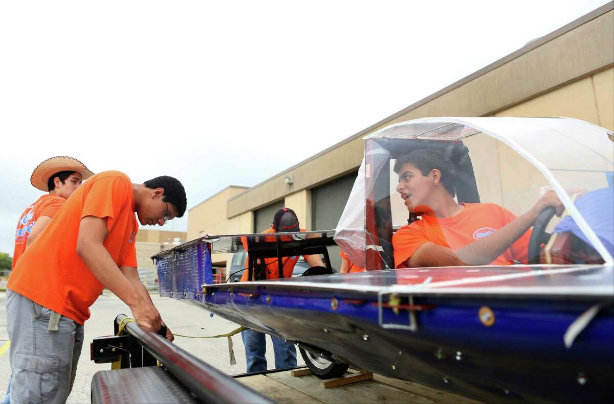 Ricardo Sanchez, right, watches as Jean-Luc Yohi, 16, adjusts a ratchet strap to tie down the solar car Helios 2 for transport on Friday, July 11, 2014, at James Madison High School in San Antonio. Helios 2, built by the Madison Solar Car Initiative, a team of students at James Madison High School, will compete in this year's Solar Car Challenge, which begins July 18 in Fort Worth.