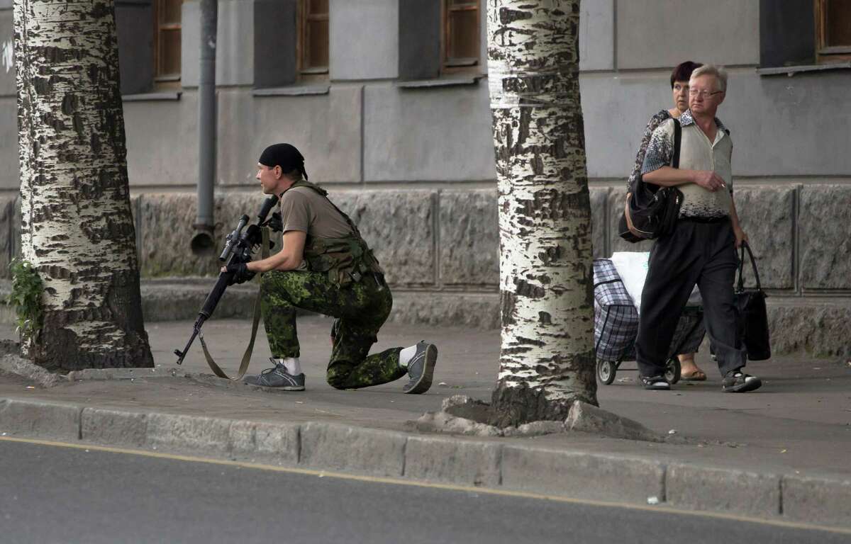 A Donetsk People's Republic fighter stands guard near a shopping mall damaged by an explosion in the city of Donetsk, eastern Ukraine Friday, July 11, 2014. On Friday afternoon a bomb exploded in a central shopping mall injuring one person. (AP Photo/Dmitry Lovetsky)