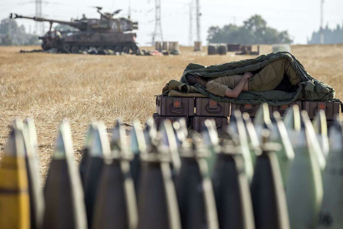 An Israeli soldier catches a nap Friday on a stack of ammunition boxes near a 155mm cannon along the Jewish nation's southern border with the Gaza Strip following Israeli airstrikes on militant Hamas targets. The operation, "Protective Edge," is the biggest Israeli military offensive on Gaza since November 2012.