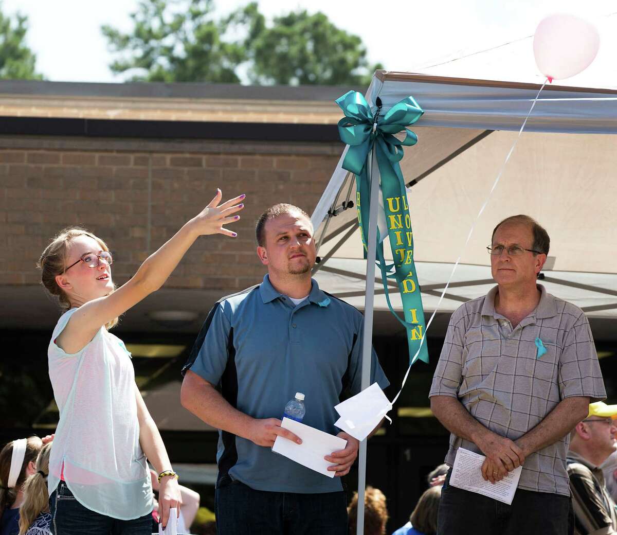 Cassidy Stay, lone survivor of the mass shooting of her parents and siblings, lets a balloon go during a community memorial celebrating the lives of the Stay family at Lemm Elementary School Saturday, July 12, 2014, in Spring. She is standing next to Drew Lyons, center, and Roger Lyons.