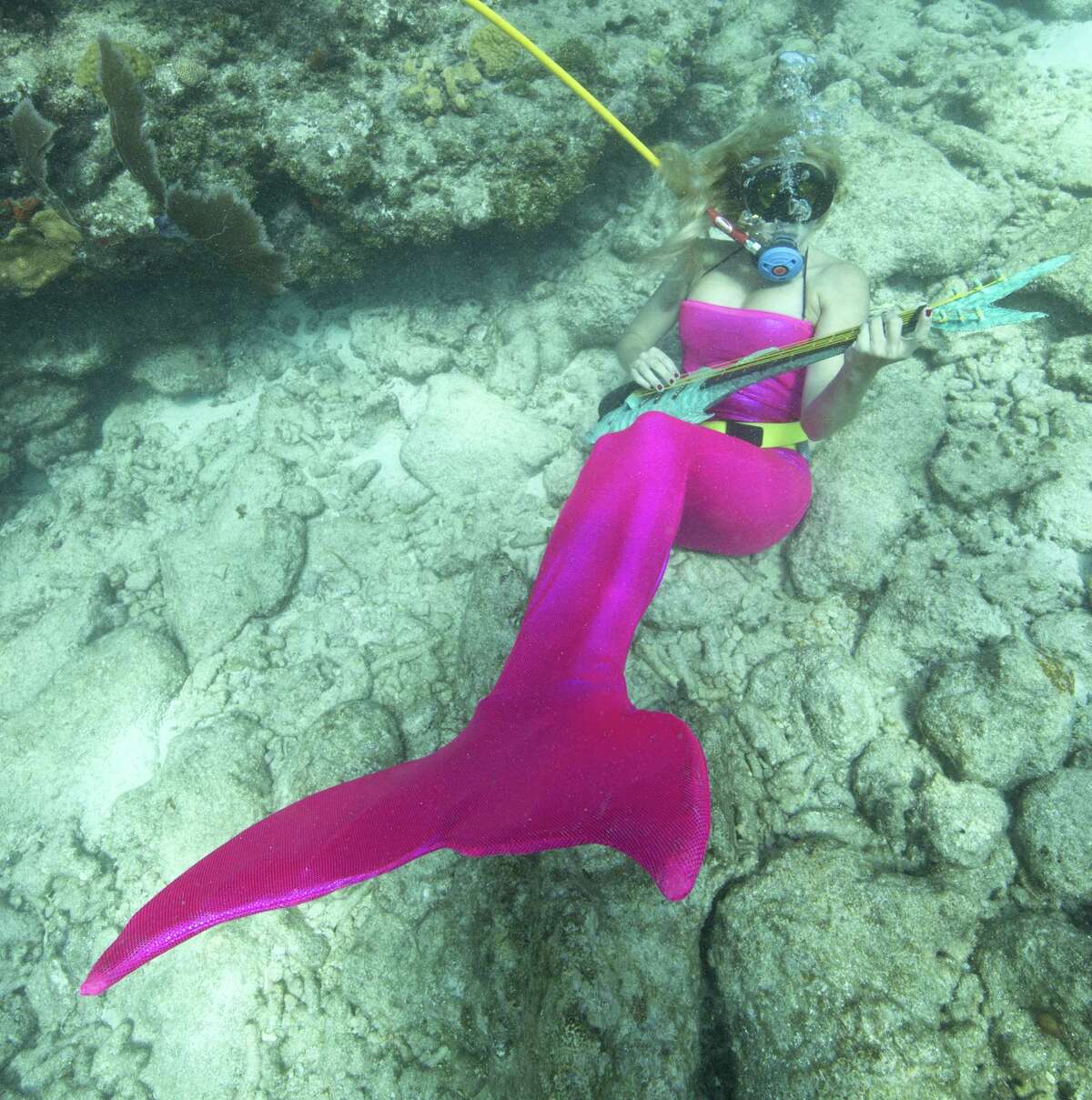 In this photo provided by the Florida Keys News Bureau, Samantha Langsdale, costumed as a mermaid, pretends to play a mock musical instrument at the Lower Keys Underwater Music Festival on Saturday, July 12, 2014, in the Florida Keys National Marine Sanctuary. The subsea concert at Looe Key Reef, about six miles south of Big Pine Key, Fla., attracted nearly 500 divers and snorkelers to listen to a local radio station's four-hour broadcast piped beneath the sea via underwater speakers. (AP Photo/Florida Keys News Bureau, Bob Care)