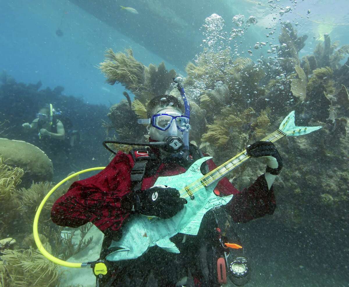 In this photo provided by the Florida Keys News Bureau, Mike Limerick pretends to play a mock musical instrument at the Lower Keys Underwater Music Festival on Saturday, July 12, 2014, in the Florida Keys National Marine Sanctuary. The subsea concert at Looe Key Reef, about six miles south of Big Pine Key, Fla., attracted almost 500 divers and snorkelers to listen to a local radio station's four-hour broadcast piped beneath the sea via underwater speakers. (AP Photo/Florida Keys News Bureau, Bob Care)