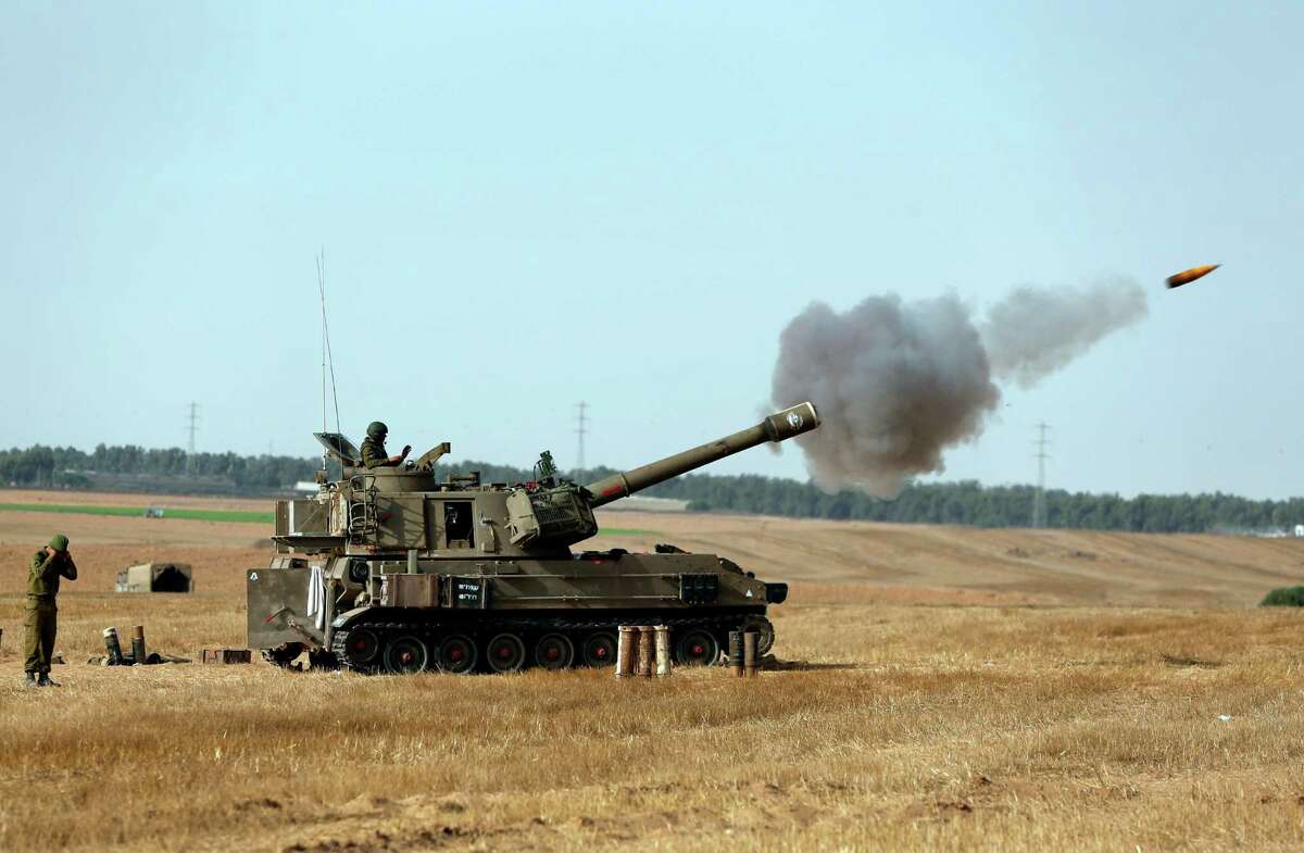 Israeli soldiers on a mobile artillery unit fire a shell towards Gaza at a position on the Israel-Gaza border, Saturday, July 12, 2014. Israeli airstrikes overnight targeting Hamas in Gaza hit a mosque its military says concealed the militant group's weapons, in an offensive that showed no signs of slowing down. Israel launched its campaign five days ago to stop relentless rocket fire on its citizens. While there have been no fatalities in Israel, Palestinian officials said overnight attacks raised the death toll there to over 120, with more than 920 wounded. (AP Photo/Lefteris Pitarakis)