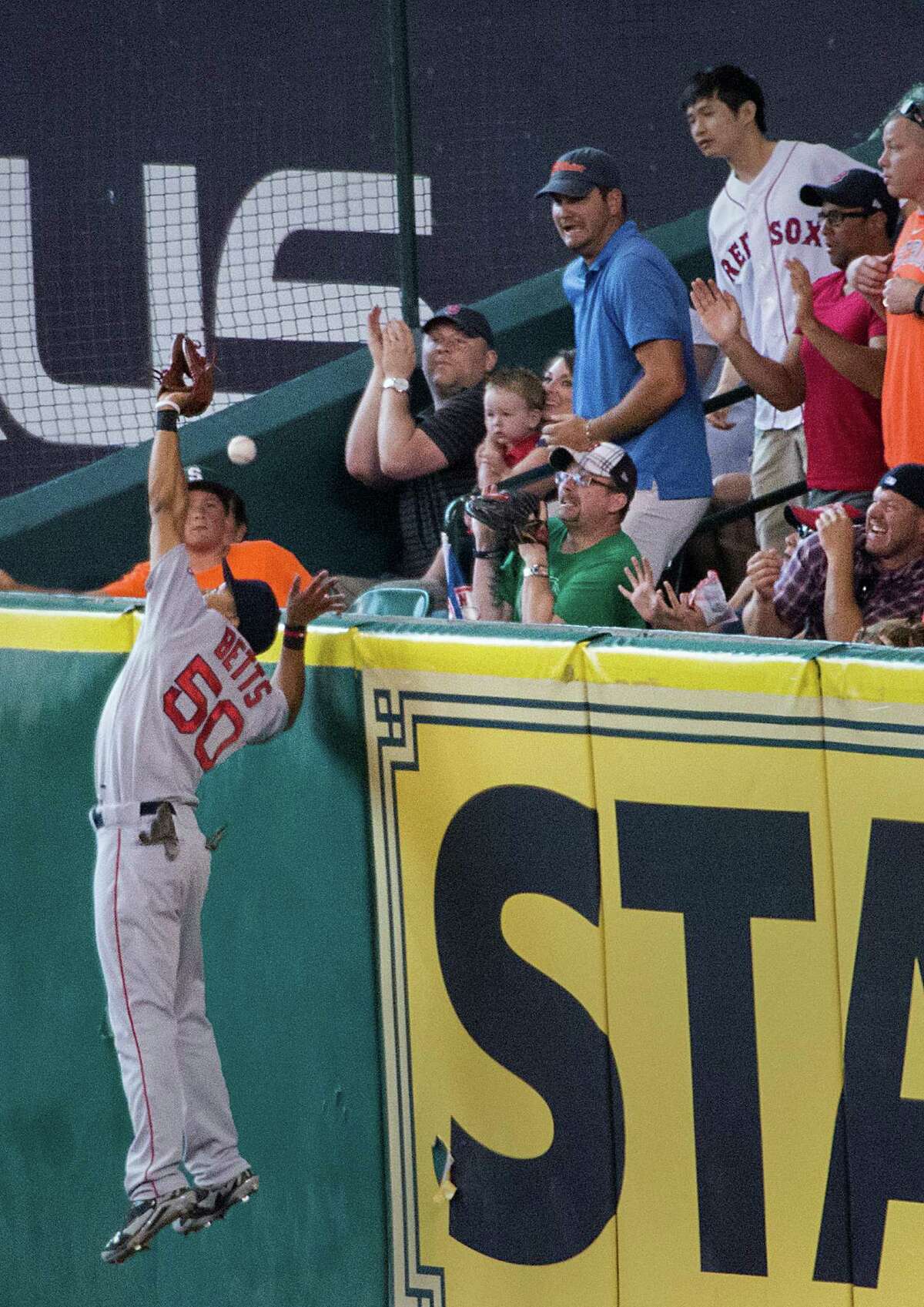 Red Sox right fielder Mookie Betts (50) makes a bid to deny the Astros' Jason Castro a home run in the third inning. But Betts comes up empty-handed, much to the fans' delight Saturday at Minute Maid Park.