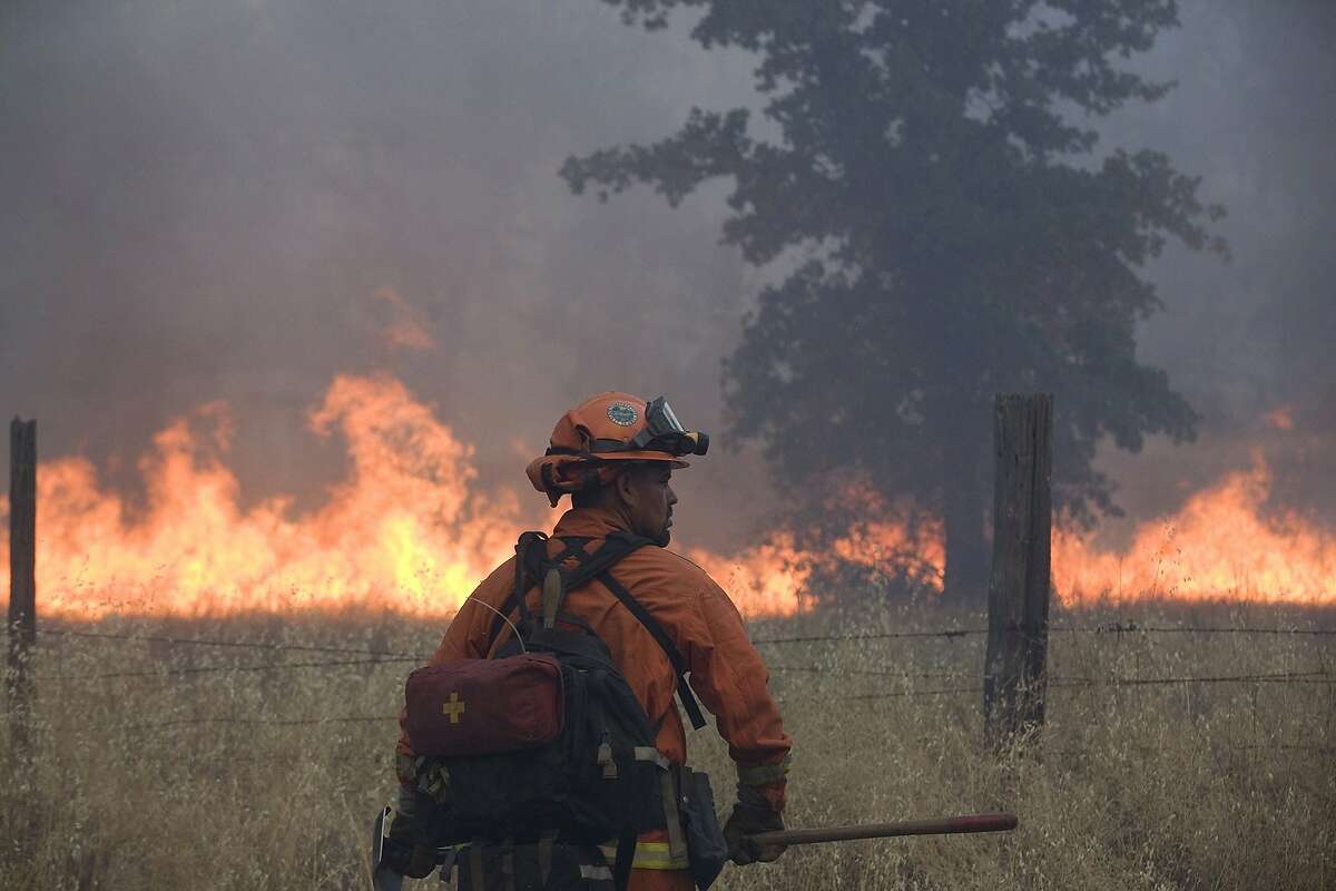 FILE - In this July 11, 2014 photo, a member of an inmate firefighting crew works on the Bully fire near Ono, Calif. A 27-year-old man who was allegedly at an illegal marijuana plot is suspected of starting a wildfire that has burned about 6 square miles of forested land in northern California. Freddie Alexander Smoke III was arrested Saturday, July 12, 2014 and accused of recklessly causing a fire and with marijuana cultivation, both felonies, according to the California Department of Fire and Forestry Protection. The so-called Bully fire has since grown to 3,700 acres and destroyed six structures, CalFire officials said. The blaze, which is burning in steep terrain, was just 10 percent contained Sunday morning. (AP Photo/The Record Searchlight, Greg Barnette)