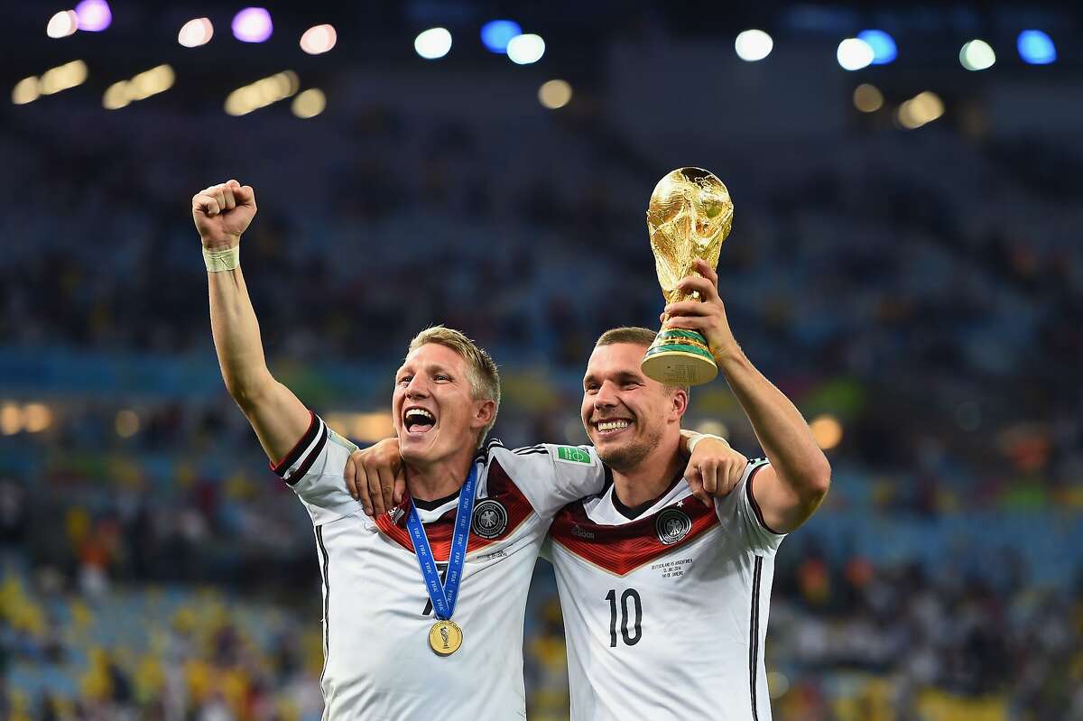 RIO DE JANEIRO, BRAZIL - JULY 13: Bastian Schweinsteiger and Lukas Podolski of Germany celebrate with the World Cup trophy after defeating Argentina 1-0 in extra time during the 2014 FIFA World Cup Brazil Final match between Germany and Argentina at Maracana on July 13, 2014 in Rio de Janeiro, Brazil. (Photo by Laurence Griffiths/Getty Images)