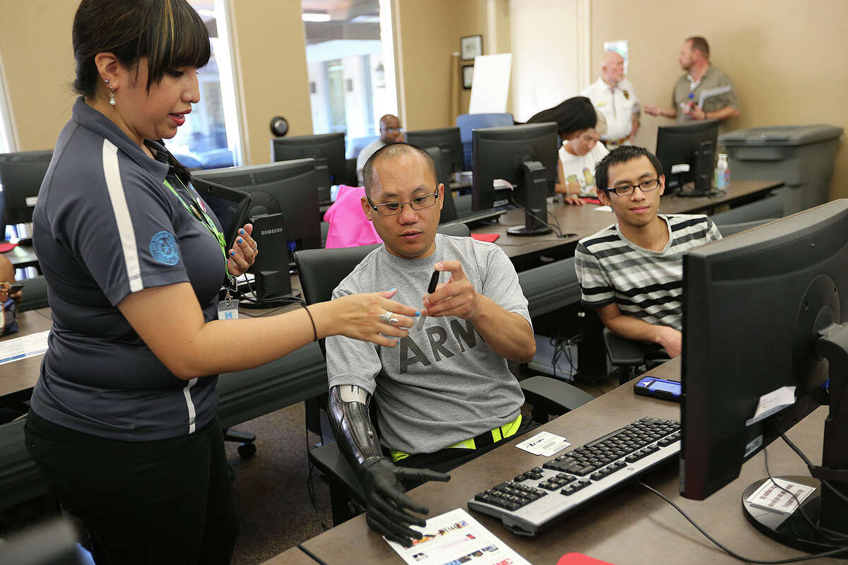 Bexar Bibliotech Technology Assistant Lynette Barrera, left, helps out Staff Sgt. Nhut Nguyen, of Boston, sign up for the digital library at the Warrior and Family Support Center of Joint Base San Antonio-Fort Sam Houston, Monday, July 14, 2014. Bexar County opened the digital library at the center and will make available its content to military personnel and families of personnel under going treatment and recovery at Brooke Army Medical Center. On the right is Tung Mai, Nguyenâ€™s brother visiting from Boston.