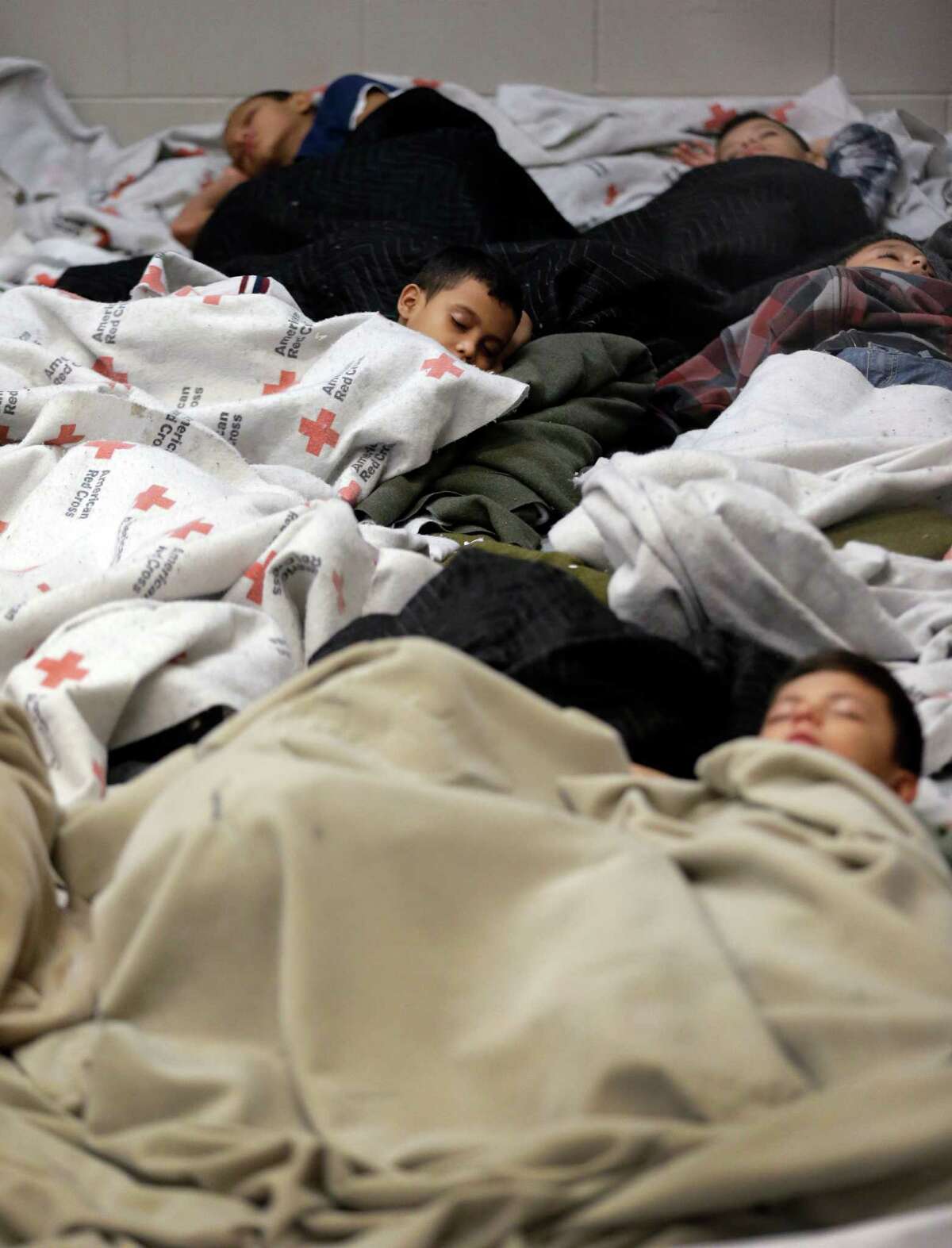 BROWNSVILLE, TX - JUNE 18: A detainees sleep in a holding cell at a U.S. Customs and Border Protection processing facility, on June 18, 2014, in Brownsville,Texas. Brownsville and Nogales, Ariz. have been central to processing the more than 47,000 unaccompanied children who have entered the country illegally since Oct. 1. (Photo by Eric Gay-Pool/Getty Images)