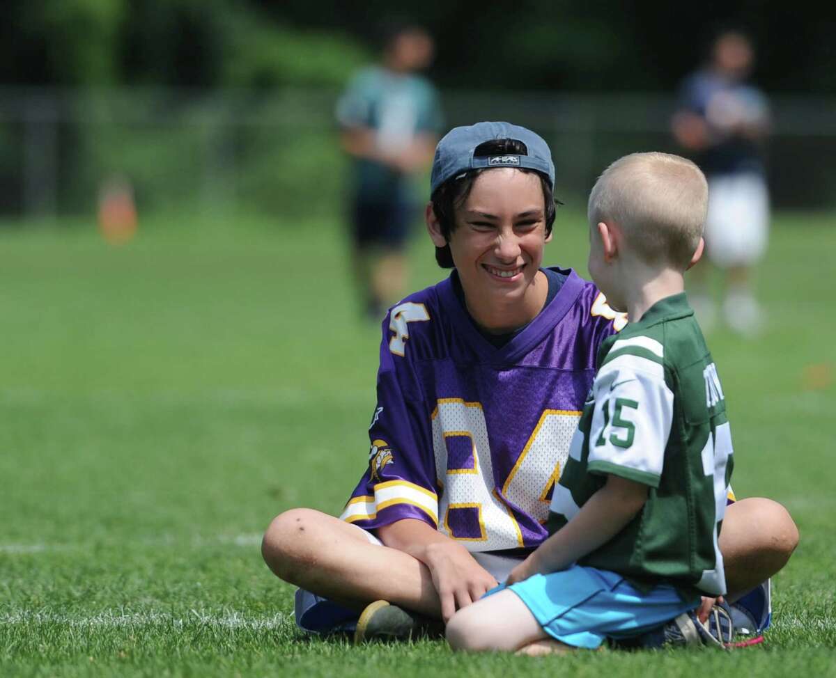 Volunteer Dan Hamula, left, 17, talks with Aidan Walker, 6, during the Newtown Parks & Recreation flag football camp at the Fairfield Hills Campus in Newtown, Conn. Friday, July 11, 2014. The Parks & Recreation department holds five week-long camps, run by instructor Jeffrey Tolson, for kids ages six to 14. The kids get right into the action from day one and the week culminates with a playoff-style league that crowns a Super Bowl champion.