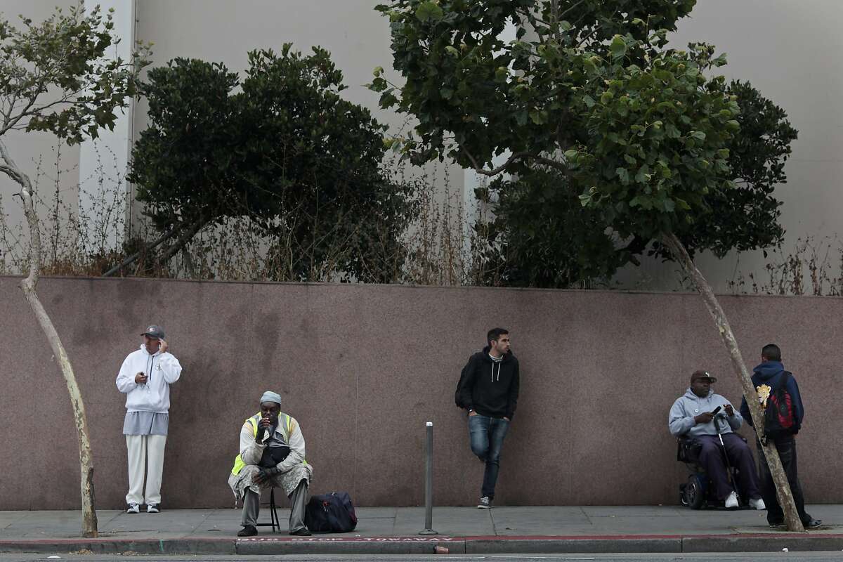 Commuters wait for the bus near the corner of Van Ness and O'Farrell St. on Tuesday, July 15, 2014 in San Francisco, Calif. Plans to create level-boarding platforms at bus stops along Van Ness have been cut because they are too expensive to maintain.