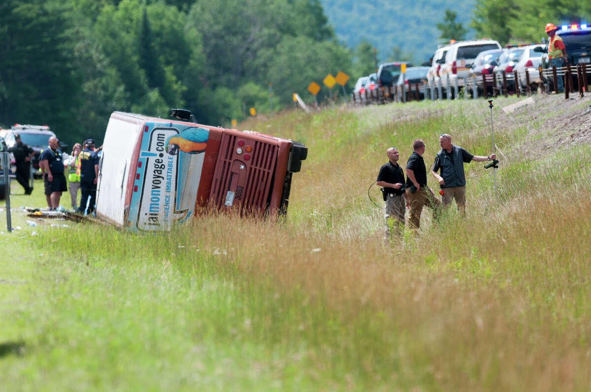 Emergency personnel investigate the scene of fatal bus crash near exit 29 of the Northway in the southbound lanes Friday morning, July 18, 2014, in North Hudson, N.Y. One person was killed and 55 injured. The bus was traveling from Quebec to New York City. (Tom Brenner/ Special to the Times Union)