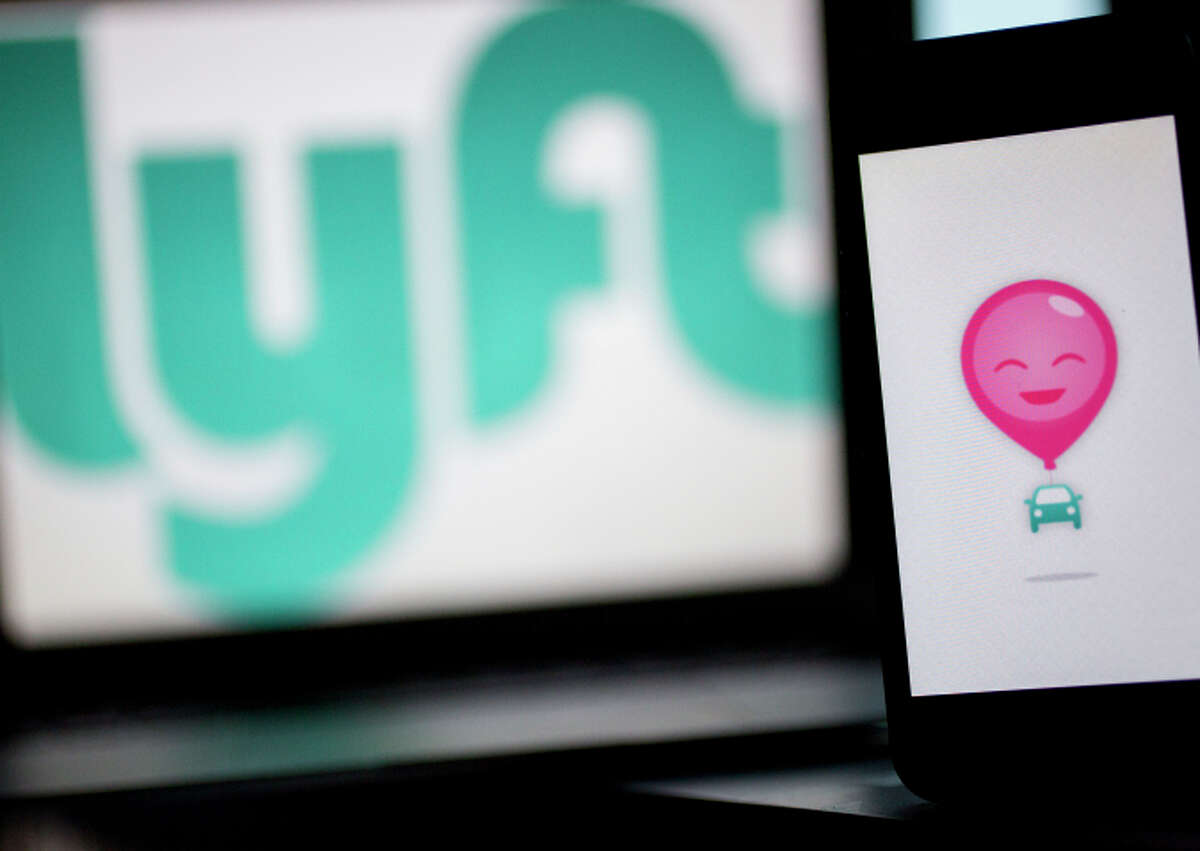 The Lyft Inc. logo and application (app) is displayed on an Apple Inc. iPhone 5s and MacBook Air for an arranged photograph in Washington, D.C., U.S., on Wednesday, July 9, 2014. 