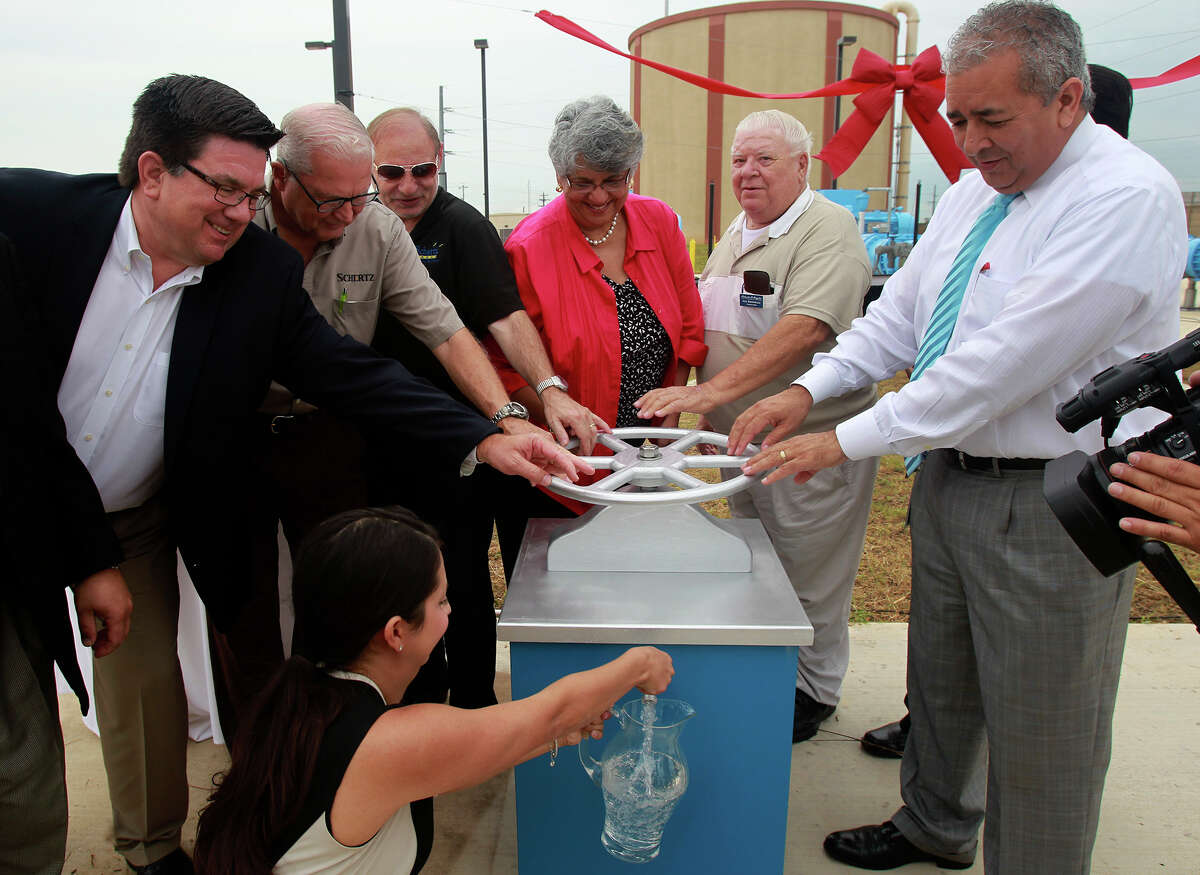 San Antonio Water System President and CEO Robert Puente (far right) turns a ceremonial valve Friday July 18, 2014 during the dedication of a SAWS pump station in Schertz, Texas that will bring water to northeast San Antonio from Gonzales County. After the water is treated at the Schertz-Seguin treatment facility, almost 5.2 billion gallons of water per year will enter SAWS pipelines and be distributed in San Antonio. On the far left is Seguin City Manager Douglas Faseler.