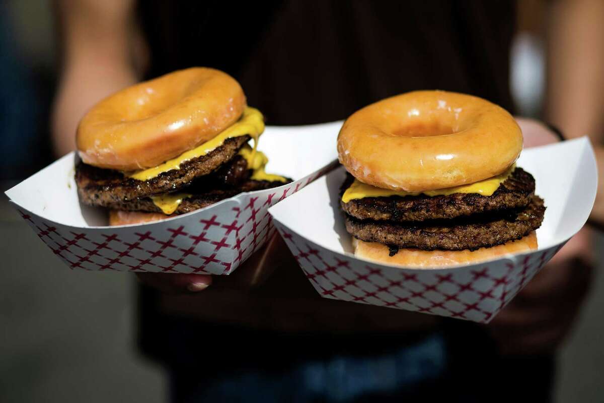 An attendee presents his purchase of two Krispy Kreme bacon cheeseburgers - with buns subbed out for donuts - at the annual Bite of Seattle Friday, July 18, 2014, in Seattle, Wash.