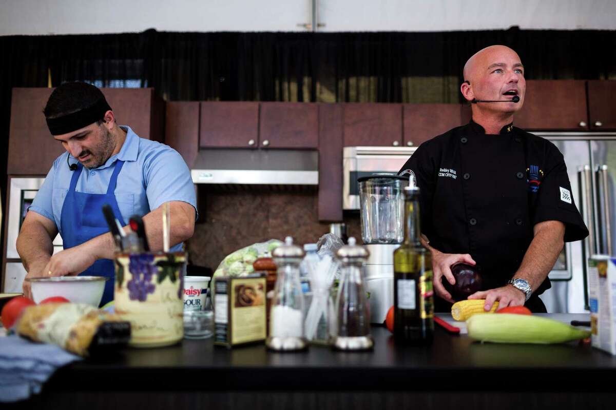 Chefs Michael Roddey, right, and Nick Novello , left, go head-to-head during a cook-off at the annual Bite of Seattle Friday, July 18, 2014, in Seattle, Wash.