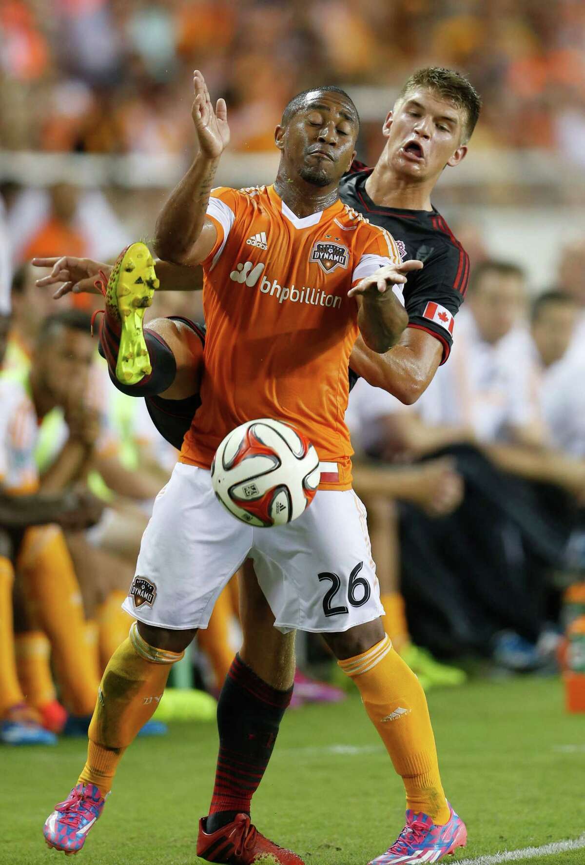 Houston Dynamo midfielder Corey Ashe (26) and Toronto FC defender Nick Hagglund (17) battle to keep the ball in play during the first half of the MLS soccer game at BBVA Compass Stadium, Saturday, July 19, 2014, in Houston.