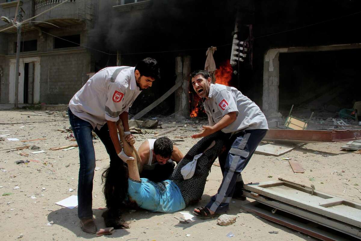 Palestinian medics help carry a wounded woman in front of the Al Mughrabi family building following an Israeli air strike that hit their home in Rafah, Sunday, July 20, 2014. One woman and her 2-year-old grandson were killed when an Israeli airstrike struck the home of the Mughrabi family northeast of Rafah, according to the Red Crescent.Latest from AP: Scores dead in first major ground battle in Gaza