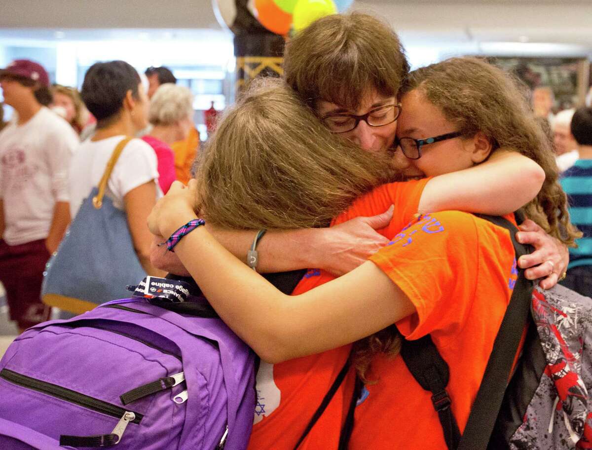 Relieved parent Wendy Suttin hugs her twin daughters, Beth and Sara, arriving back Monday from a three-week trip in Israel. The Suttin twins were part of a travel party of 48 from Houston's Congregation Emanu El that returned home. Unlike many other trips for Jewish American teens during the current conflict in the State of Israel, this traveling party taking part in the first Shirley Barish Memorial Israel trip - which includes five staff members and 43 students from the Congregation's Helfman Religious School - there were no plans of an early return.
