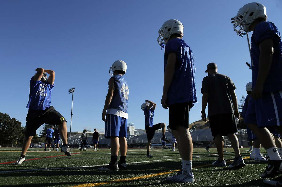 Varsity football players practice non-impact tackling drills at Acalanes High School football practice on Monday, July 21, 2014, in Lafayette, Calif. The football coaching philosophy at Acalanes has been to focus on technique and mechanics rather than on physical impact, as coaches had long ago chosen to emphasize safety. On Monday, Gov. Jerry Brown signed a bill into law that limits middle and high school sports to two days a week for full-contact football practices.