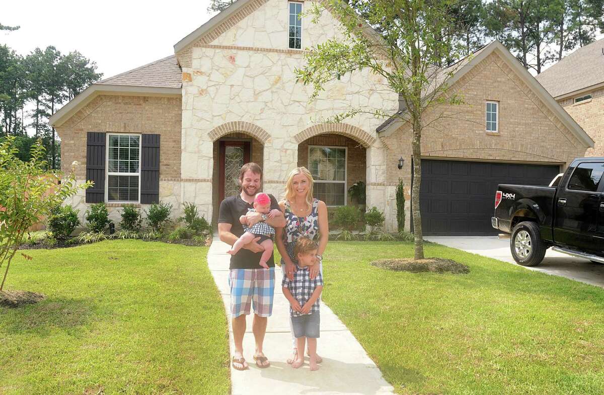 Matt and Nina MeFarlane and their children Hadley and Knox in front of their new home in the Sawmill Ranch neighborhood in Spring.