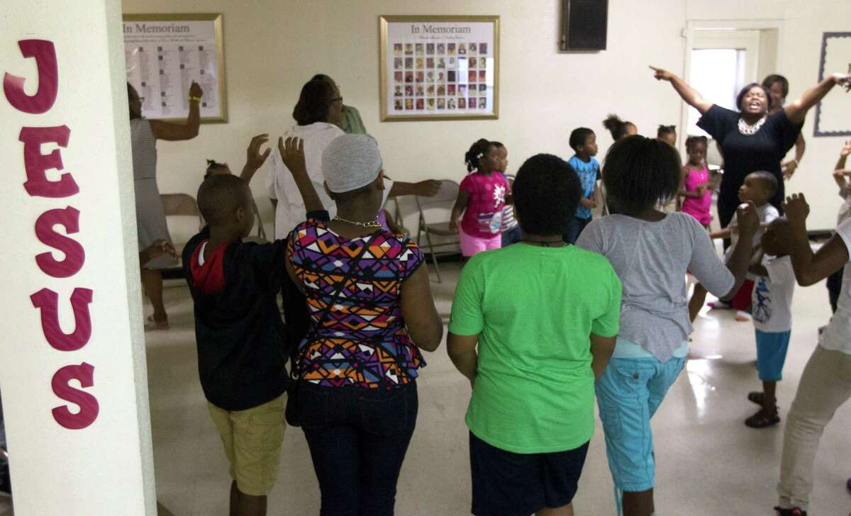 Participants enjoy singing and dancing to religious music during an evening vacation bible school at Brown Chapel A.M.E. on Monday, July 21, 2014, in Houston.
