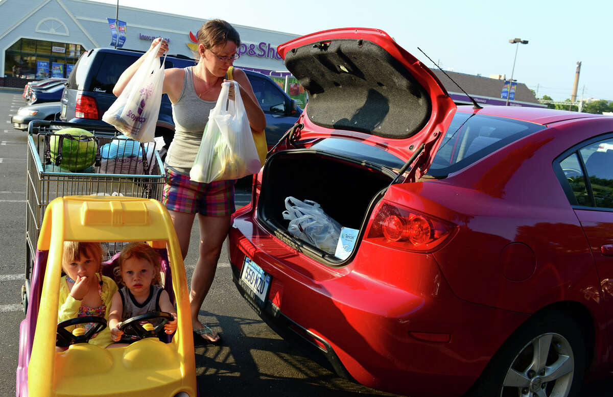 Colleen Caceres, of Stratford, loads groceries into her car as her children Zoe, 4, and Dante, 1, wait in the cart at the Stop and Shop supermarket off of East main Street in Stratford, Conn. on Tuesday July 22, 2014. Several fruits, like peaches, are being recalled at some chain stores like Stop & Shop, Trader Joe's, and Sam's Club because of listeria.