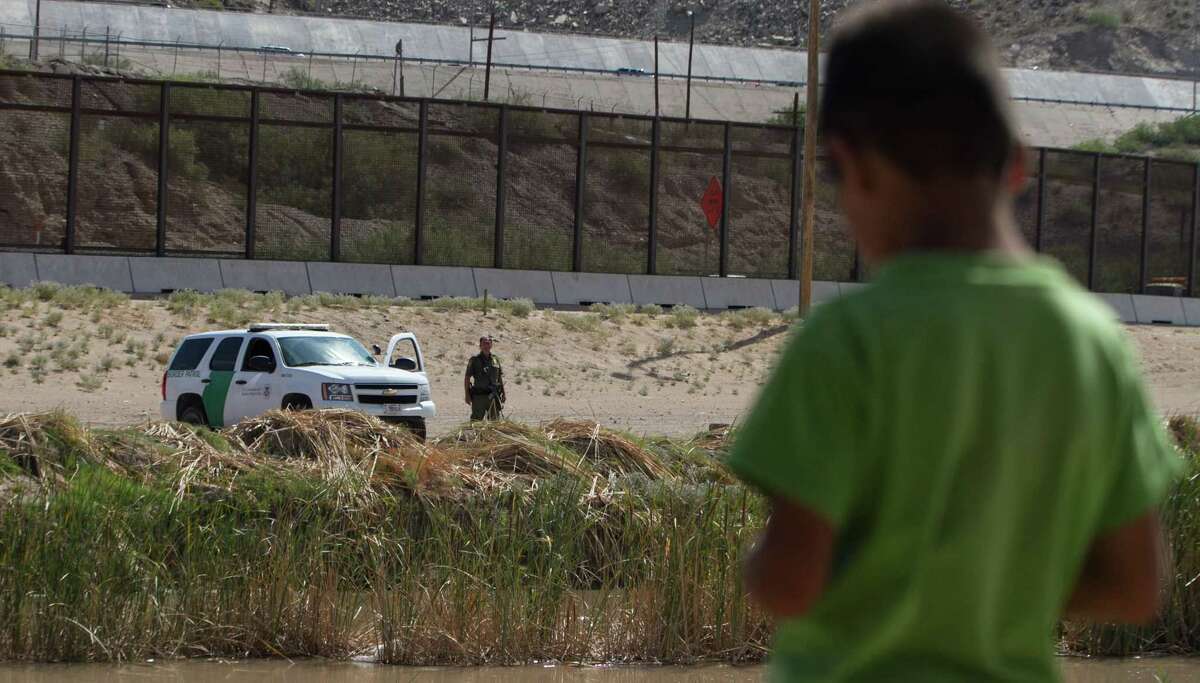 A Mexican boy looks at a member of the U.S. Border Patrol standing guard on the border between El Paso in the United States and Ciudad Juarez in Mexico,