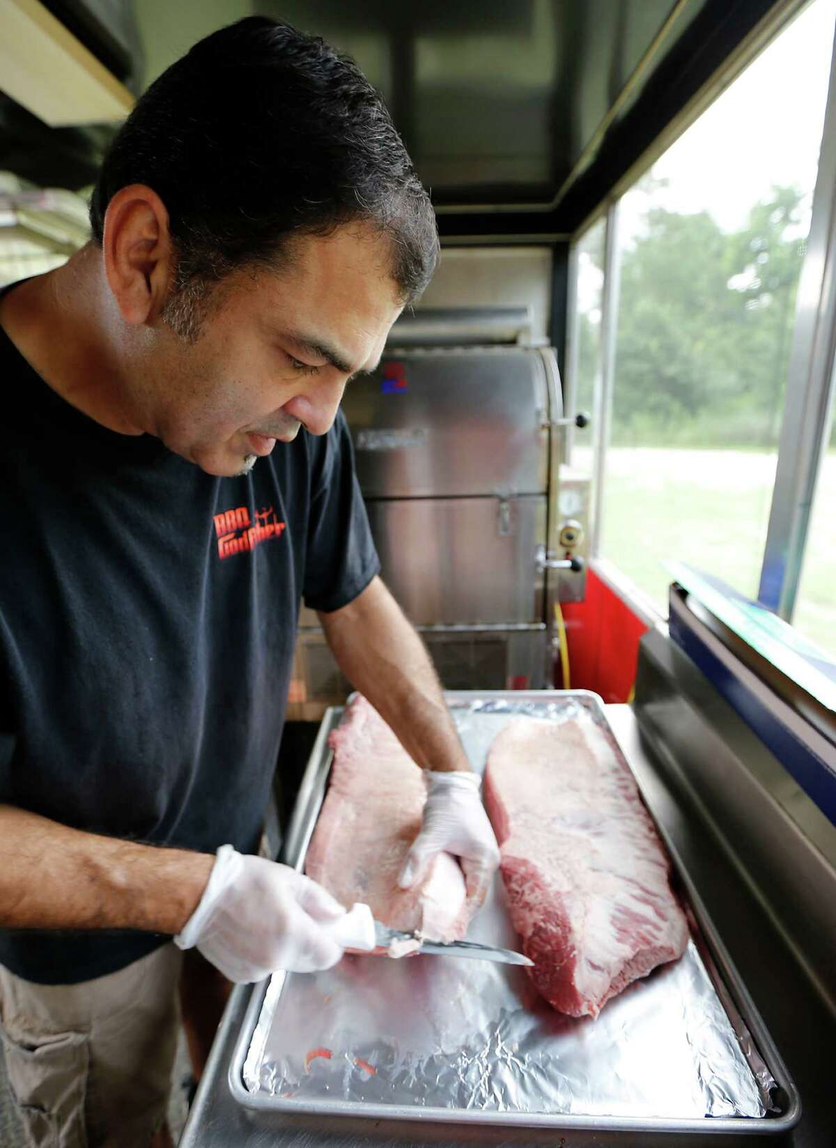 BBQ Godfather owner Tony Faour trims a brisket.