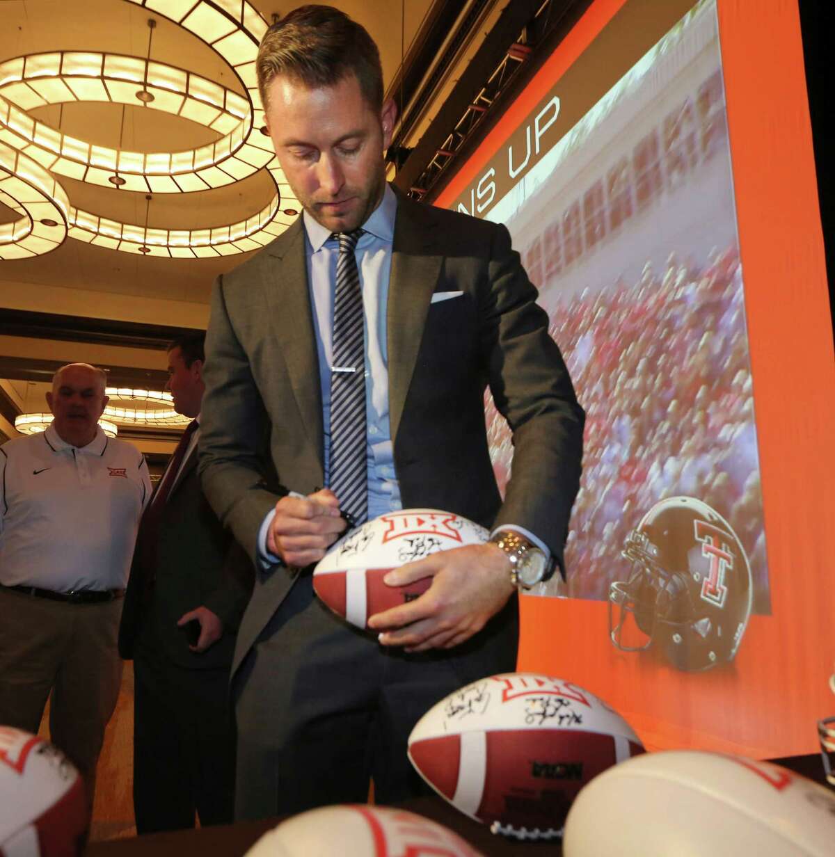 Proof the watch is fake ... Texas Tech football coach Kliff Kingsbury signs a football during the NCAA college Big 12 Conference football media days in Dallas, Monday, July 21, 2014. The watch seen on his wrist could be a $100 fake. (AP Photo/LM Otero)
