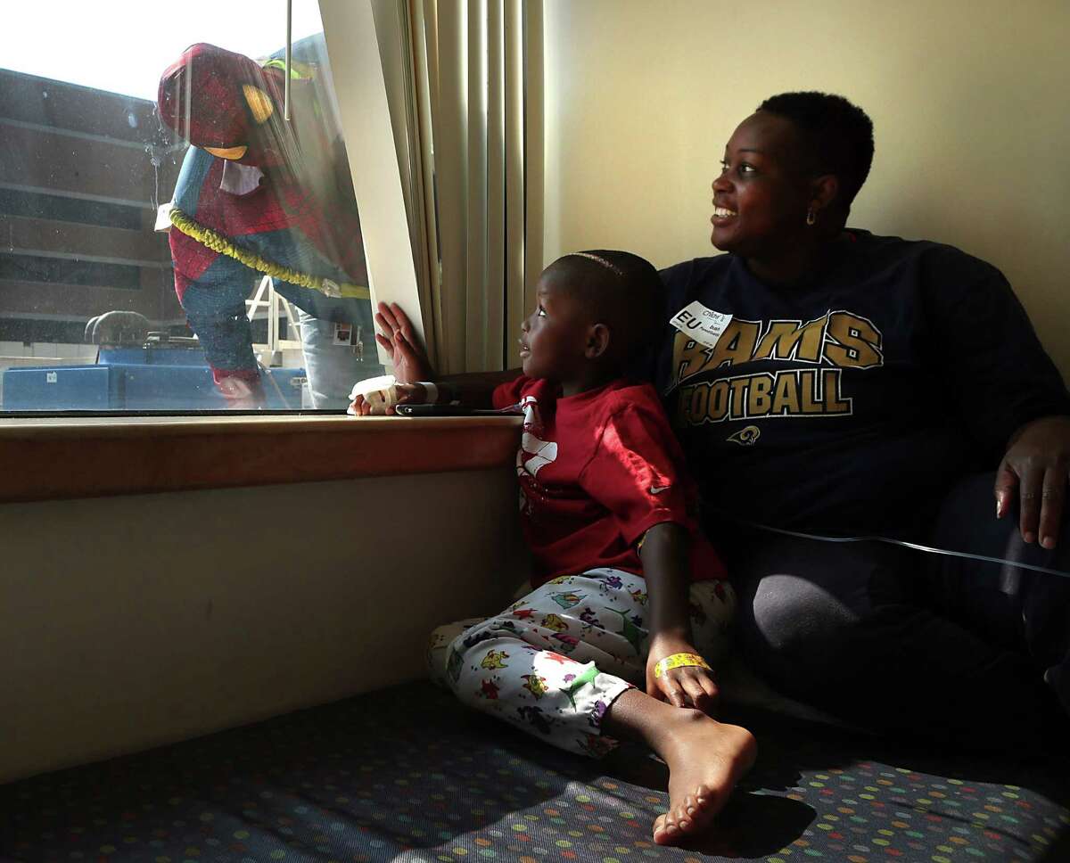 Matt McGehee, wearing a Spider-Man costume, peers into the window to surprise Isaiah Bush and his mother Tamekia Bush, of Belleville, as he washes the windows at St. Louis Children's Hospital in St. Louis.