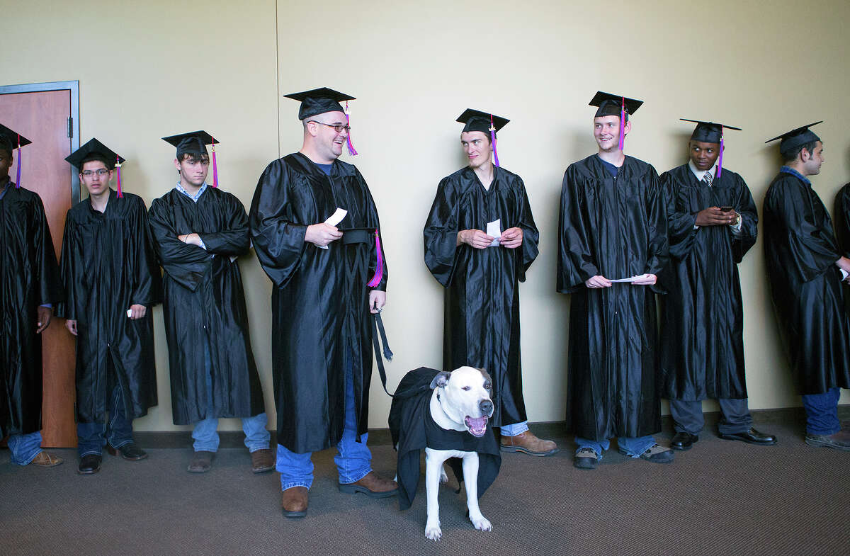 Kolby Thompson and his specially trained psychiatric service dog Thor, wait outside before a graduation ceremony at Fallbrook Church, Friday, July 25, 2014, in Houston. Kolby is an Iraq, Afghanistan, Korea, Kuwait, Fort Bragg and Fort Bliss veteran who now lives with PTSD. Thor helps mitigate his stress.
