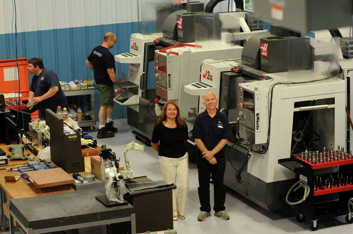 Laura and Dave Marasco, co-owners of West-Conn Tool, pose on the production floor in front of a couple of 5-axis CNC maching centers in their new location in Shelton, Conn. The business, which manufactures medical devices, has just moved to this location from Stratford.