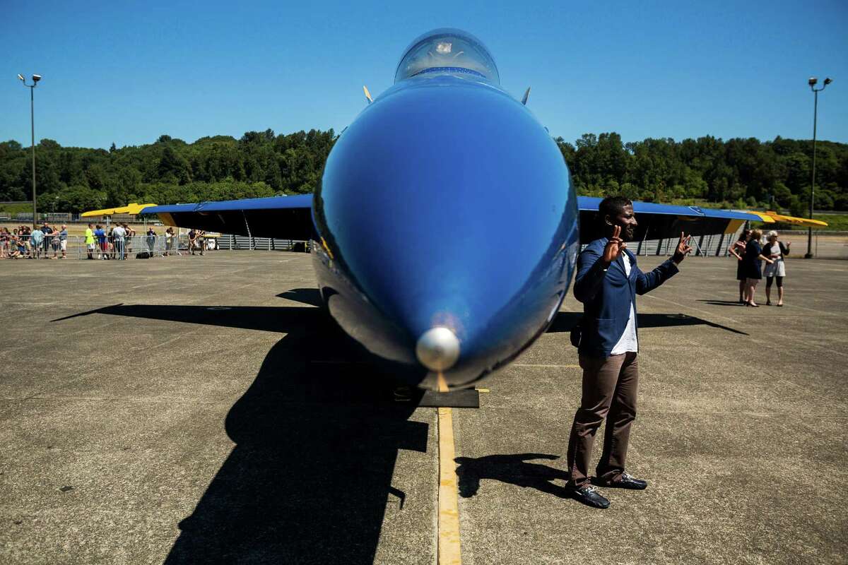 Onlookers pose for pictures by the U.S. Navy Blue Angels at Boeing Field Monday, July 28, 2014, in Seattle, Wash.