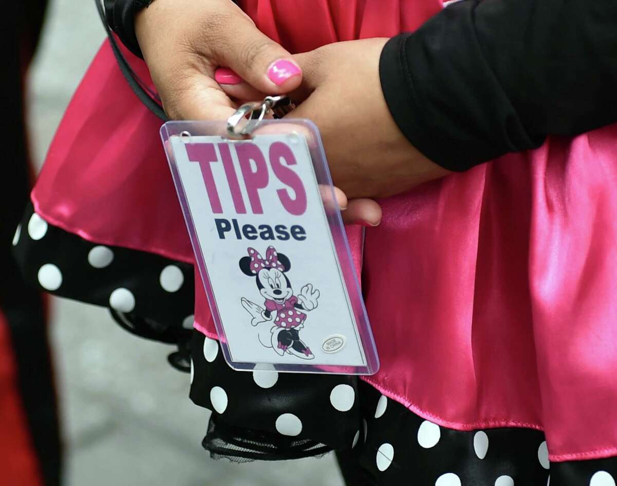 A Minnie Mouse character holds a small sign that she shows to tourists after she poses for photographs with them July 28, 2014 in New York's Times Square. The panhandler characters pose for tourists and work for tips, which can sometimes lead to disputes, like the Spider-Man character arrested on July 26, for assaulting a police officer after an argument with a tourist over the amount of the tip. 